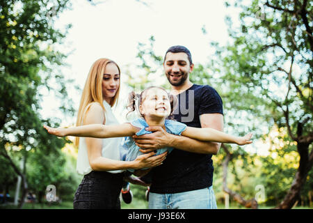 Joyeux Heureux jeune famille père, mère et fille s'amuser en plein air, jouer ensemble en parc d'été. Banque D'Images