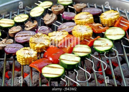 Brochettes avec un mélange de légumes sur les briquettes de charbon chaude du barbecue Banque D'Images