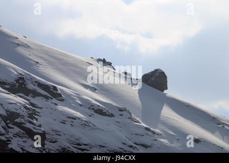 Un énorme rocher naturel perché sur la pente couverte de neige d'une montagne Banque D'Images