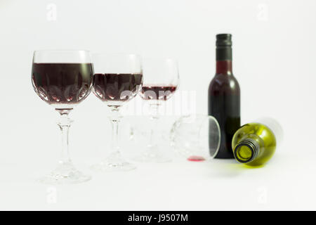 Concept de la consommation d'alcool, l'alcoolisme et l'abus par une ligne de beaux verres de cristal rempli de vin rouge, un plein et une bouteille vide. Banque D'Images