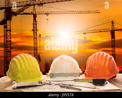 Grue en chantier de construction et la table de travail de l'ingénieur civil avec l'outil d'écriture et de construction plan Banque D'Images