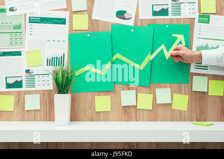 Businessman de la composition d'un tableau financier réussi avec la flèche qui monte, il est à l'aide de coupes de papier vert, eco business et la réussite financière concept Banque D'Images