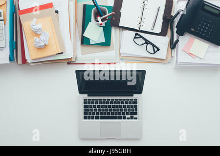 S'opposant à un bureau complet désordre nettoyer le bureau bien rangé, des tas de paperasse sur le dessus et un ordinateur portable à bas, d'affaires et technologie concept Banque D'Images