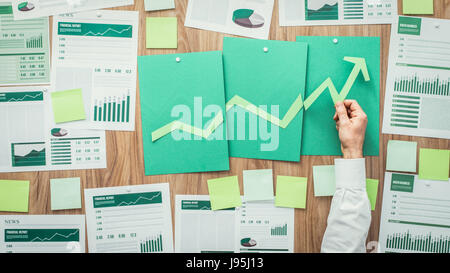 Businessman de la composition d'un tableau financier réussi avec la flèche qui monte, il est à l'aide de coupes de papier vert, eco business et la réussite financière concept Banque D'Images