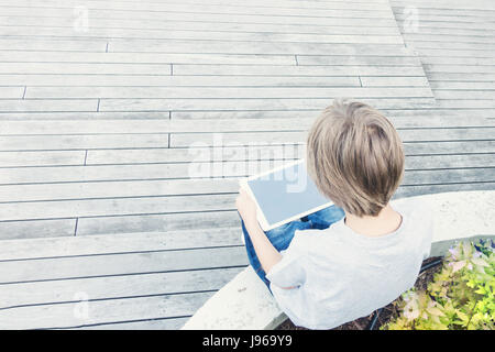 Enfant avec ordinateur tablette assis à l'extérieur. Vue d'en haut Banque D'Images