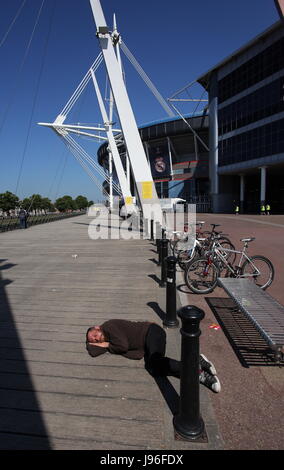 Un sans-abri dort sur le sol à l'extérieur le Stade National du Pays de Galles (aka Principauté Stadium) Banque D'Images