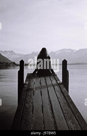 Woman looking at Lake Geneva view pendant l'hiver en noir et blanc à partir du bord d'une rampe en bois Banque D'Images