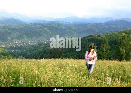 Jeune femme avec un bouquet de fleurs sauvages dans un pré de montagne Banque D'Images