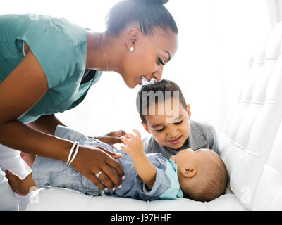 Mère avec deux fils (2-5 mois, 2-3) sur canapé Banque D'Images
