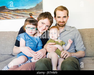 Portrait de parents avec ses filles (4-5, 2-3) sitting on sofa Banque D'Images