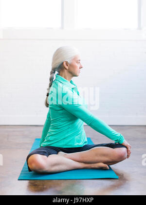 Senior woman practicing yoga on mat Banque D'Images