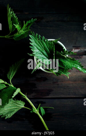 Ortie feuilles sur une table de bois préparés pour la cuisson Banque D'Images