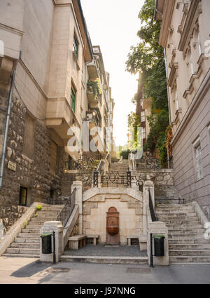 Vue à travers une rue étroite avec des bâtiments historiques des deux côtés et de la lumière du soleil à la fin. Lieu : Budapest, Hongrie, Europe. Banque D'Images