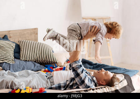 Smiling man holding son fils dans l'air au-dessus de lui-même Banque D'Images
