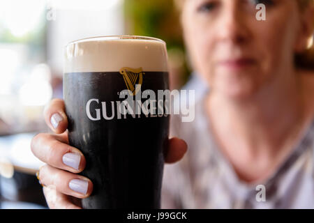 Une femme est titulaire d'une pinte de Guinness dans un pub irlandais Banque D'Images