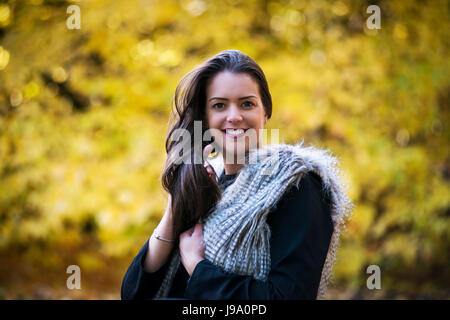 Jeune femme admirant les couleurs chaudes de l'automne dans les bois entourée d'arbres et de laisser d'érable canadien érables acer Japonais, les tons de rouge, orange Banque D'Images