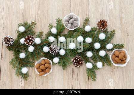 Amandes enrobées de chocolat dans des petits bols blancs disposés autour de décoration de Noël. Banque D'Images