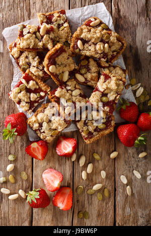 Des bars aux fraises avec du gruau, arachides et graines de citrouille sur la table. vertical Vue de dessus Banque D'Images