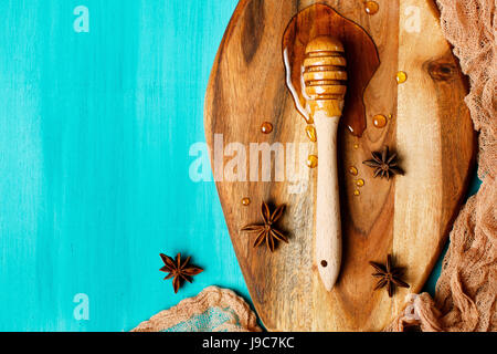 Le miel avec une cuillère sur une planche sur un fond bleu, vue du dessus, copy space Banque D'Images