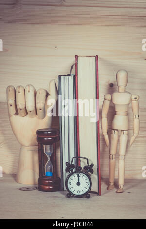 Marionnette en bois Sablier Horloge Alarme avec livre sur un bureau en bois Banque D'Images