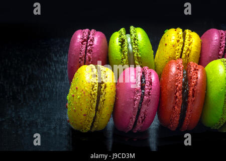 Rangée de macarons colorés français sur fond noir. Banque D'Images