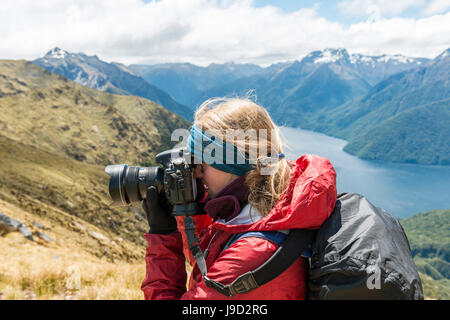 Jeune femme de prendre une photo, Kepler Track, Fiordland National Park, Southland, Nouvelle-Zélande Banque D'Images