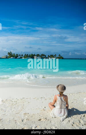 Femme assise sur une plage de sable blanc, eau turquoise le Sun Island Resort, l'île de Dhiffushi, Ari atoll, Maldives Banque D'Images