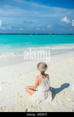 Femme assise sur une plage de sable blanc, eau turquoise le Sun Island Resort, l'île de Dhiffushi, Ari atoll, Maldives Banque D'Images