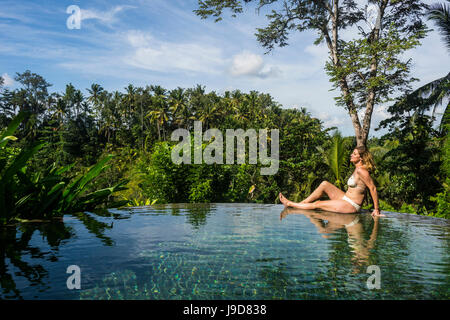 Femme bénéficiant d'une piscine à débordement au-dessus d'une vallée dans le Kamandalu Resort Ubud, Ubud, Bali, Indonésie, Asie du Sud, Asie Banque D'Images