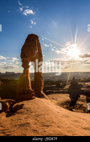 Delicate Arch avec soleil et nuages à l'heure d'or, Arches National Park, Moab, Grand County, Utah, USA, Amérique du Nord Banque D'Images