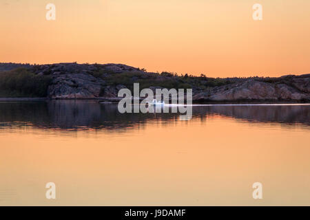 La conduite du bateau dans le coucher du soleil sur l'océan clair miroir Banque D'Images