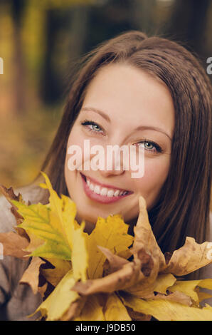 Fille de l'automne jouer à city park. Portrait de femme automne heureux belle et magnifique jeune femme en forêt en couleurs d'automne. Banque D'Images