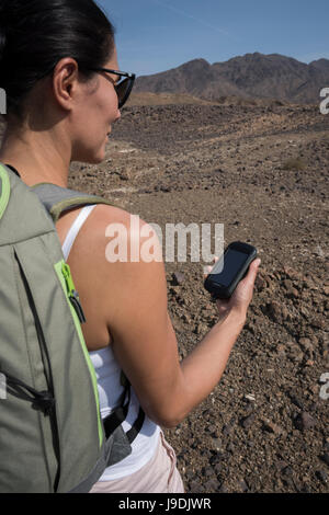 Femme à l'aide d'un GPS de poche avec les montagnes arides comme arrière-plan au cours d'un trek. L'accent sur l'unité GPS Banque D'Images