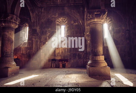 Intérieur de l'église chrétienne médiévale arménienne avec les rayons du soleil à partir de la fenêtre qui tombe sur les bougies. La religion, l'architecture, travel concept. Banque D'Images