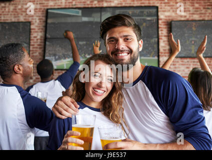 Portrait de Couple Watching jeu dans un bar sportif sur les écrans Banque D'Images