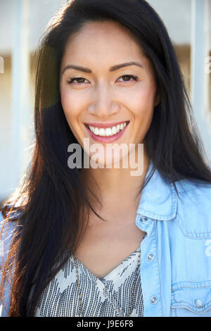 Young mixed race woman smiling outdoors, portrait Banque D'Images