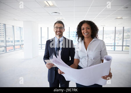 Portrait Of Businesspeople Looking At Plans dans bureau vide Banque D'Images