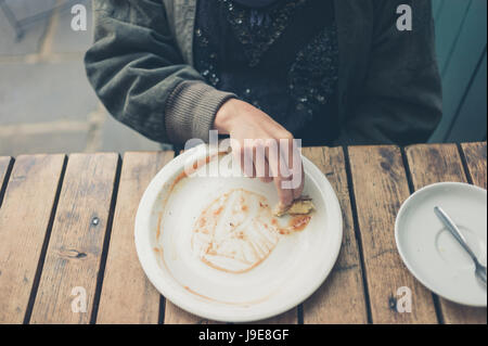 Une jeune femme est la sauce son assiette hors d'essuyage avec un morceau de pain Banque D'Images