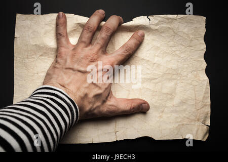 Main attraper vieux marin vide de papier froissé feuille sur fond noir, pirate site concept Banque D'Images