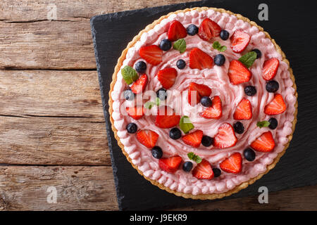 Tarte aux fruits avec de la crème fouettée, fraises et bleuets close-up sur la table horizontale vue du dessus. Banque D'Images