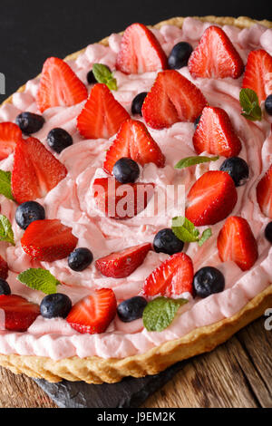 Belle tarte avec des fraises et des bleuets avec de la crème chantilly sur la table verticale. Banque D'Images