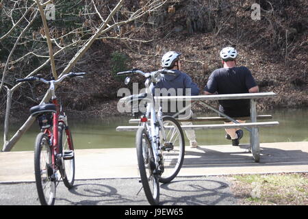 Deux hommes adultes reposant sur l'établi par la rivière après bike ride Banque D'Images