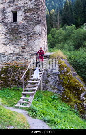 Couple en costume traditionnel géorgien en ordre décroissant des escaliers de la tour de l'amour, pour un usage éditorial uniquement, Ushguli, région de Svaneti, Géorgie Banque D'Images