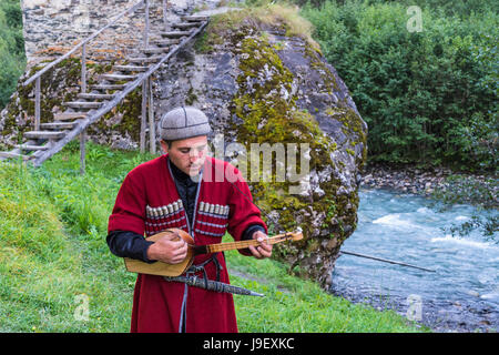 Musicien géorgien d'un groupe folklorique Panduri jouant en face de la tour de l'amour, pour un usage éditorial uniquement, Ushguli, région de Svaneti, Géorgie Banque D'Images
