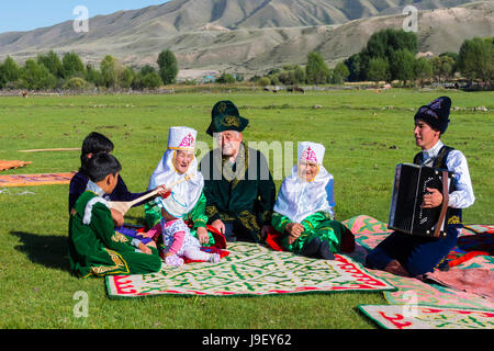 La famille kazakhe en vêtements traditionnels à écouter la musique d'un joueur d'accordéon, pour un usage éditorial uniquement, le sati village, Tian Shan, de Kazakhs Banque D'Images