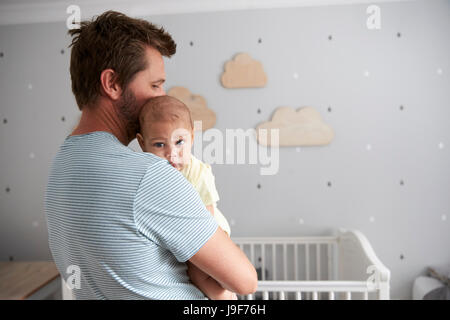 Père rassurant bébé nouveau-né Fils en maternelle Banque D'Images