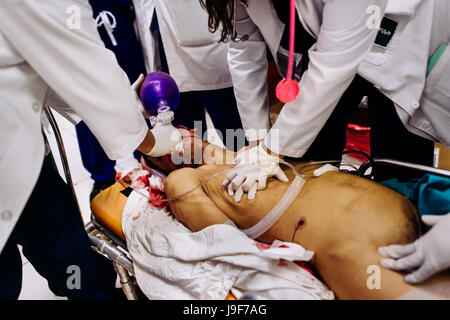 Médecins d'urgence fournissent un la réanimation d'un membre d'un gang de jeunes, avec une blessure abdominale, dans le service d'urgence d'un hôpital public à San Salvador, El Salvador, 16 décembre 2015. Banque D'Images