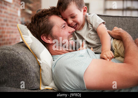 Père et fils de câlins sur canapé ensemble Banque D'Images