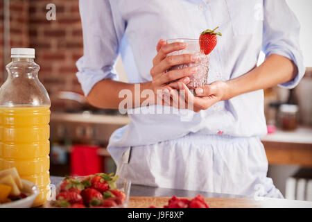Woman holding strawberry smoothie, mid section Banque D'Images