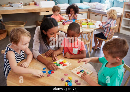 Les élèves et enseignants à l'aide de formes en bois dans l'école Montessori Banque D'Images
